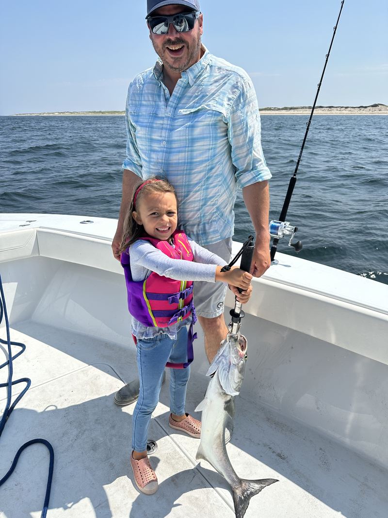 A young angler fighting a fish in her life jacket