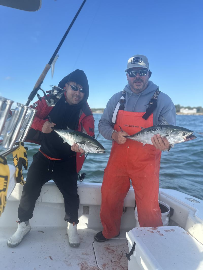 Angler and mate with a striped bass in Boston Harbor