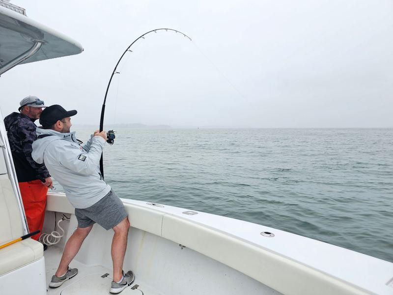 Angler fighting a fish with a bent rod on a light-tackle charter