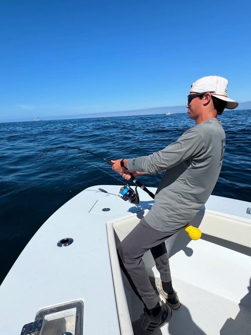 Angler fighting a striped bass from the bow of the boat