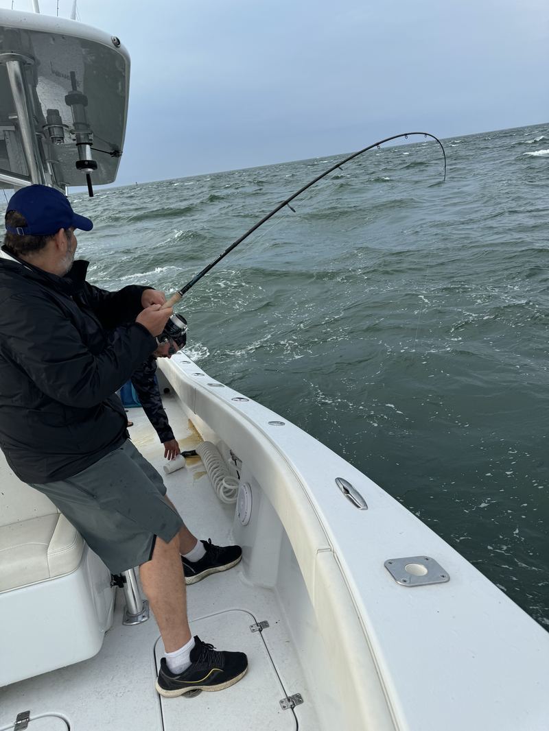 Angler fighting a striped bass in rough water
