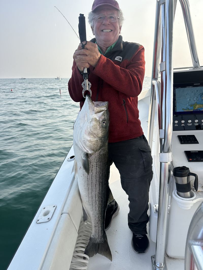 Angler holding a striped bass at the console