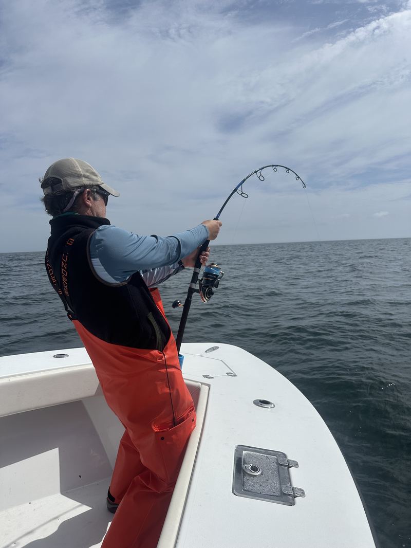 Angler in bibs fighting a striped bass