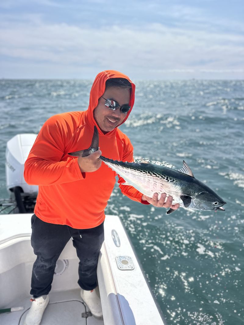 Angler in orange holding a false albacore