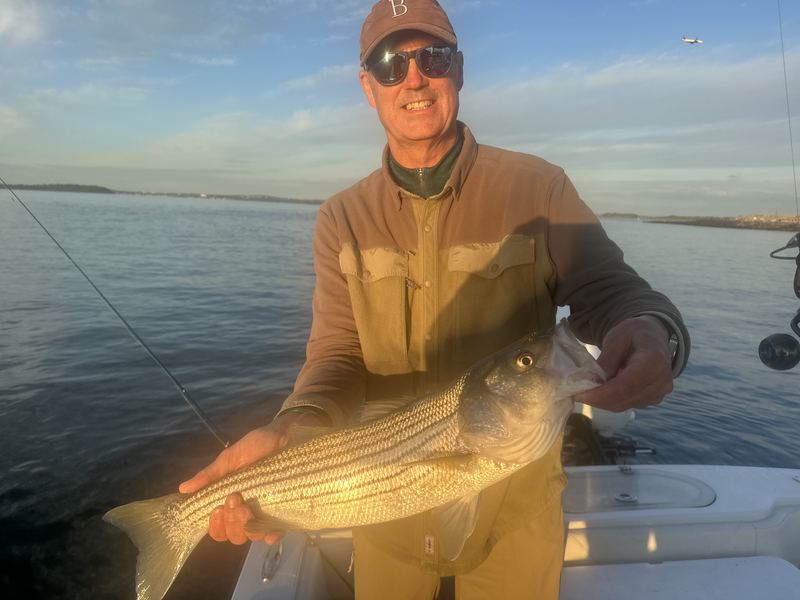 Angler with a big striped bass in golden evening light