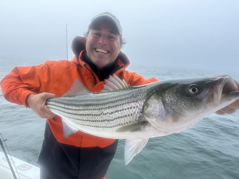 Angler with a big striped bass on the Conch 27