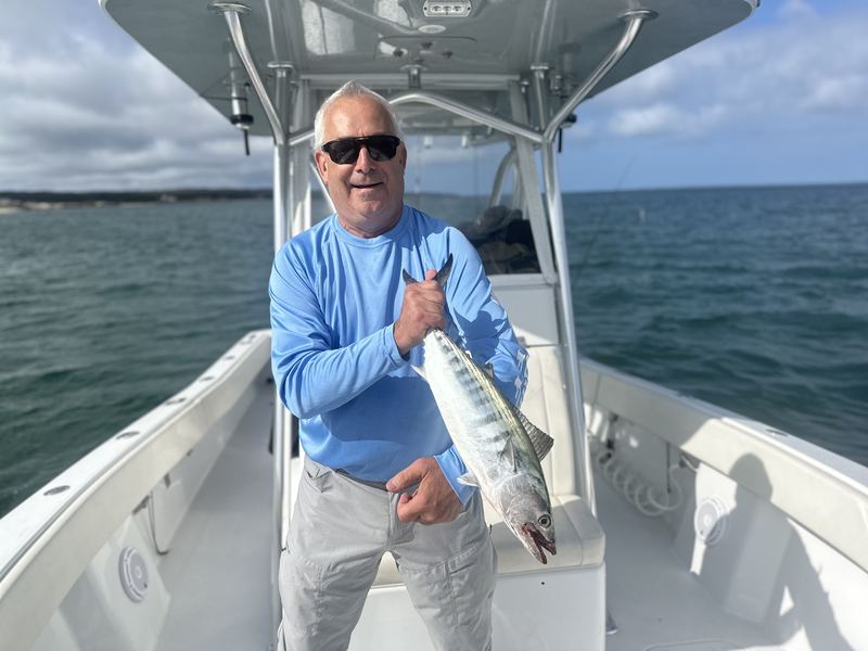 Angler with a striped bass on a center-console charter