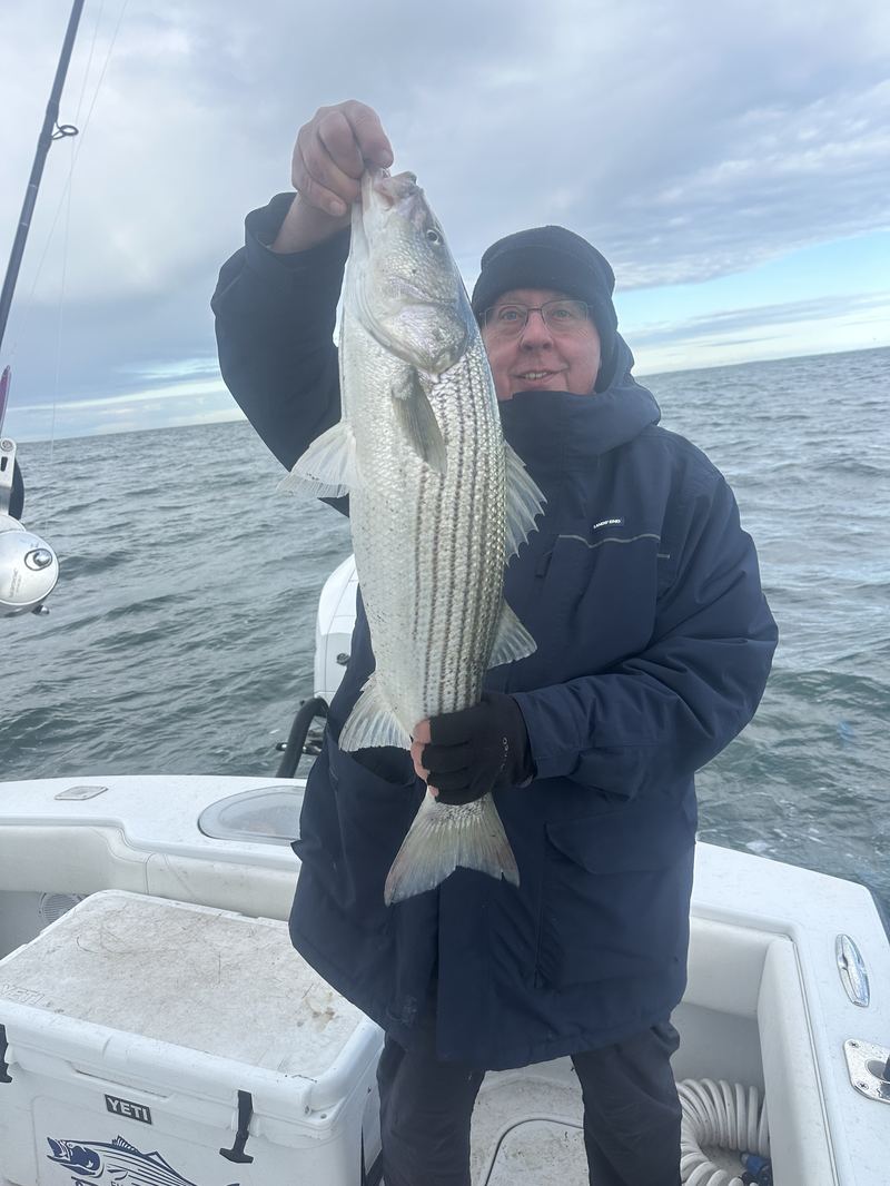 Angler with a striped bass on a cold-weather Boston charter