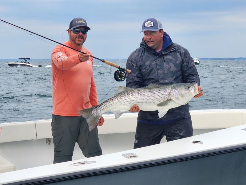 Two anglers with a big striped bass caught on the fly